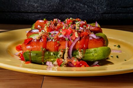 Pickle for a bun gluten free hot dogs with sliced red onions tomatoes bacon bits and chives for fancy toppingsの写真素材