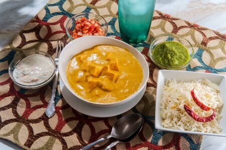 Indian paneer makhani vegetarian cheese in butter masala sauce with basmati rice green chutney and raitaの写真素材