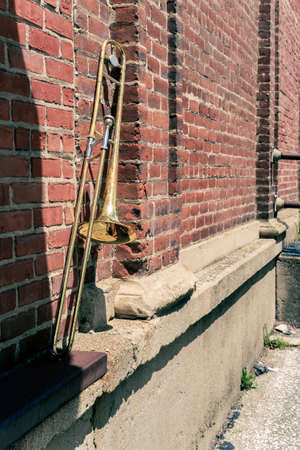 Old rusty vintage trombone leans against brick building outside jazz clubの写真素材