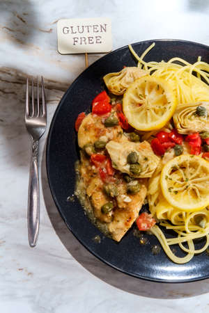 Italian chicken piccata with artichoke hearts and capers served with spaghettiの写真素材