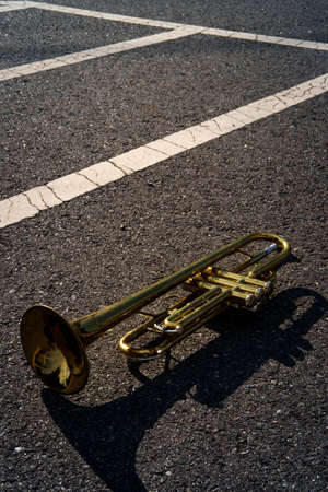 Old rusty Jazz instrument trumpet laying in the road with abstract line pattern
