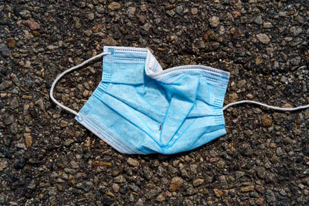 Abandoned coronavirus personal protective equipment thrown on ground in parking lot as hazardous waste and litteringの写真素材
