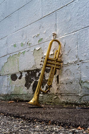 Old rusty Jazz instrument trumpet leaning against brick wall building outside clubの写真素材