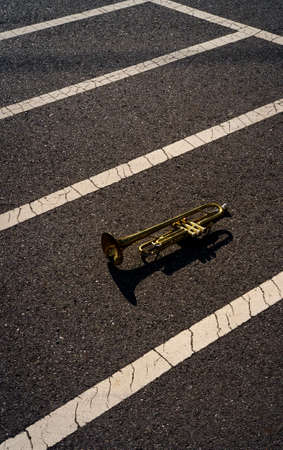 Old rusty Jazz instrument trumpet laying in the road with abstract line pattern
