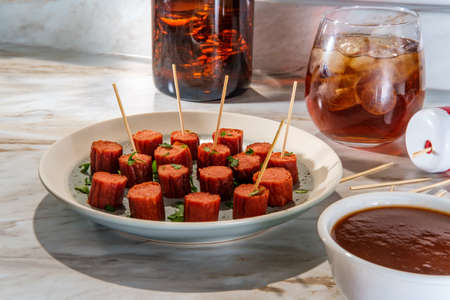 Cocktail hot dogs served with bourbon dipping sauce with glass of whiskey served straight up