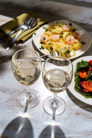 Italian fettuccine alfredo shrimp with salad and glass of white wineの写真素材