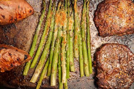 Well done beef rib boneless club steak with parmesan garlic asparagus and baked sweet potatoesの写真素材