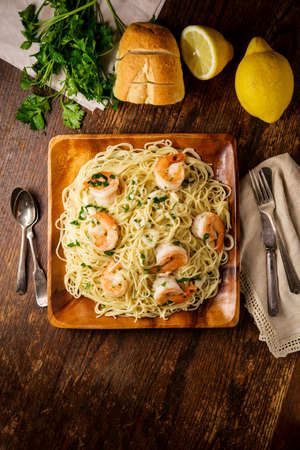 Shrimp scampi with angel hair pasta surrounded by cooking ingredientsの写真素材