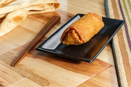 Crispy Chinese fried egg roll on wooden table