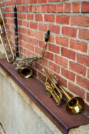 Musical instruments including trombone trumpet clarinet and saxophone on brick wall outside Jazz clubの写真素材
