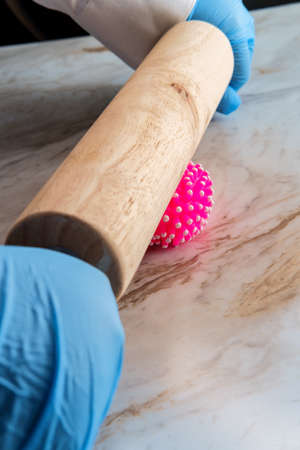 A wooden rolling pin smooshes th coronavirus as metaphor for flatten the curveの写真素材