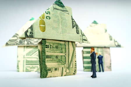 Miniature figurine businessmen and origami paper money houses for real estate and housing market conceptの写真素材