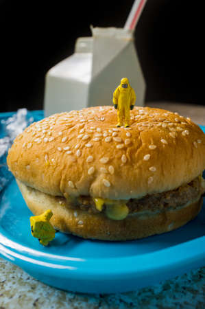 Miniature hazmat team inspecting the nutritional value of unhealthy fast food school lunchの写真素材