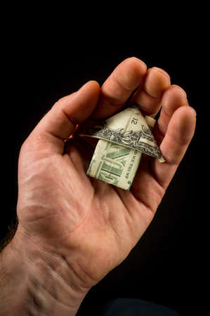 Hand holds origami paper money house for real estate and housing market conceptの写真素材