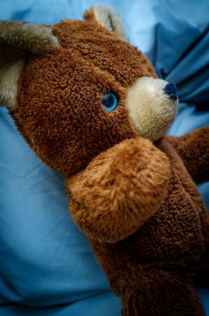 Worn old teddy bear with one blue eyeの写真素材