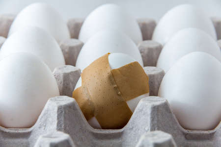 One egg has a bandage. This relates to fertility and reproductive health as well as eating healthy. The bandage can symbolize problems with both dieting and within reproduction.の写真素材