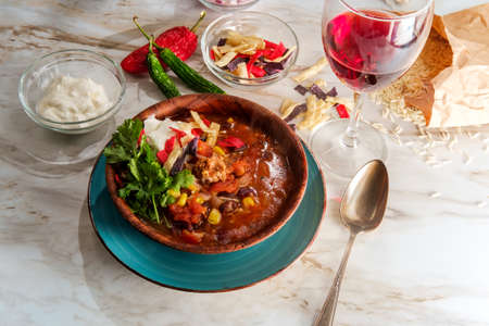 Mexican chorizo sausage taco soup with pinto black and kidney beans served with glass of red wineの写真素材