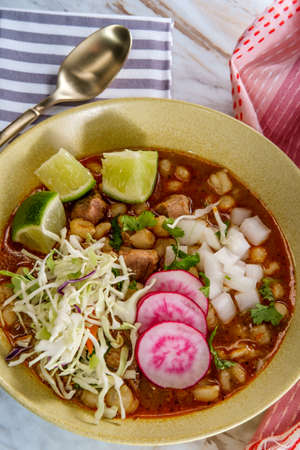 Mexican Pozole rojo pork and hominy stew with variety of fresh vegetable toppings to garnishの写真素材