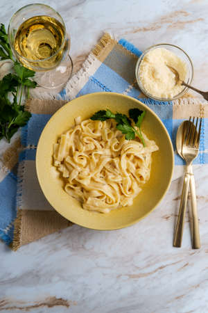 Italian fettuccine alfredo with glass of white wine and parmesan cheeseの写真素材