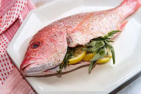 Fresh whole raw head-on red snapper stuffed seasoned and ready to be cookedの写真素材