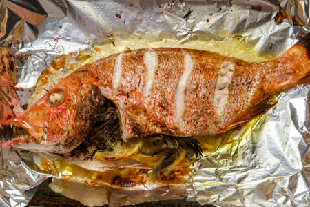 Whole head-on red snapper seafood dinner baked in the oven in tin-foilの写真素材
