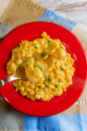Delicious shell macaroni and cheddar cheese with sweet green peasの写真素材