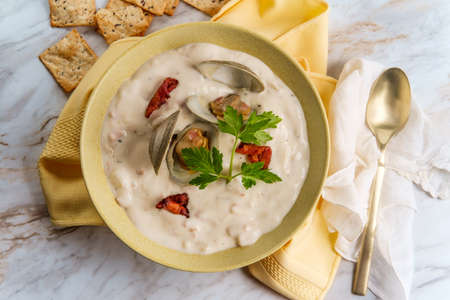 Fresh hot New England clam chowder soup with bacon and crackers