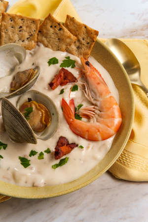 Fresh hot New England clam chowder soup with whole shrimp crackers and parsley garnishの写真素材