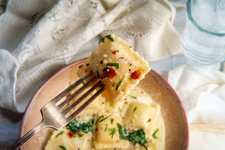 Cheese ravioli in a Tuscan creamy sauce with spinach and crushed red pepperの写真素材