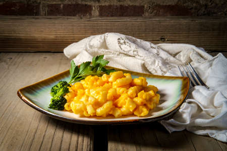 Delicious macaroni and cheese on wooden table with dramatic dark and moody lighting