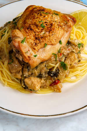 Crispy baked chicken thighs in a creamy spinach artichoke heart sauceの写真素材