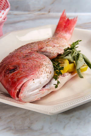 Fresh whole raw head-on red snapper stuffed seasoned and ready to be cookedの写真素材