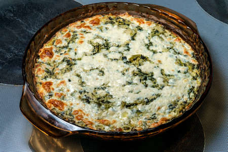Baked cheesy artichoke spinach dip in oven panの写真素材
