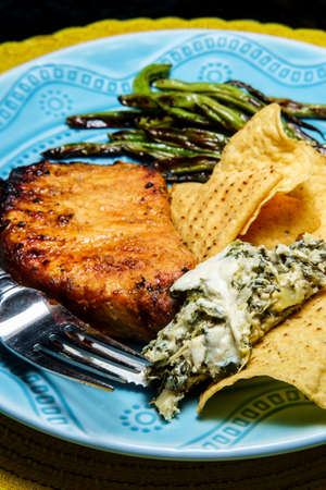 Marinated char-grilled pork chops with green beans and artichoke spinach dip
