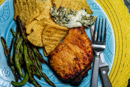 Marinated char-grilled pork chops with green beans and artichoke spinach dipの写真素材
