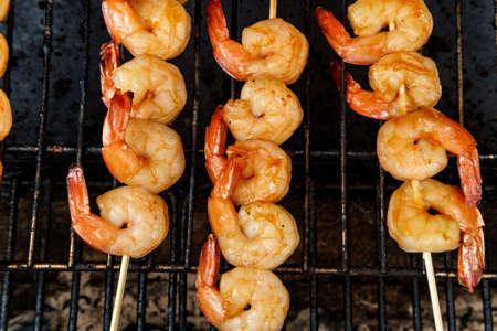 Grilling juicy bourban shrimp kebabs over charcoal on grill rackの写真素材