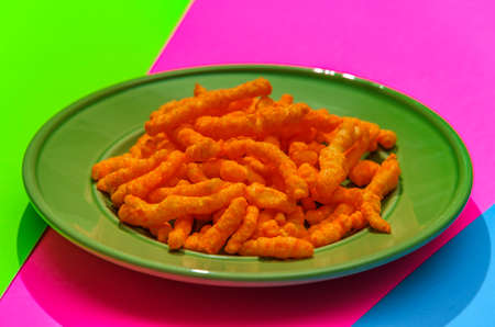 Cheese puff unhealthy junk food snack on stylized modern neon colored background