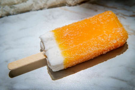 Refreshing frozen dessert Orange and cream ice pop on a stick