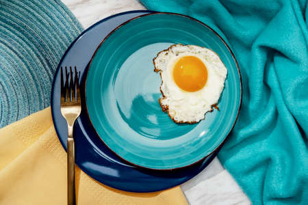 Simple sunny side up fried egg breakfast on teal plateの写真素材