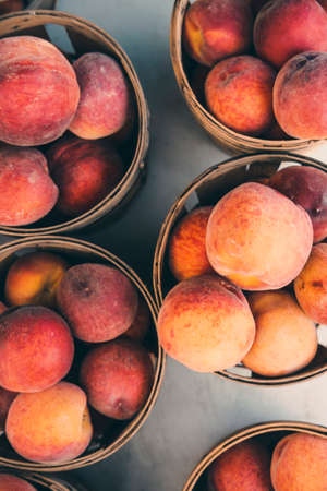 Fresh organic peaches displayed at farmers market in several baskets