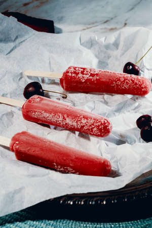 Juicy homemade black cherry icepops on parchment paperの写真素材