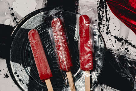 Red strawberry icepops on abstract black and white paint backgroundの写真素材