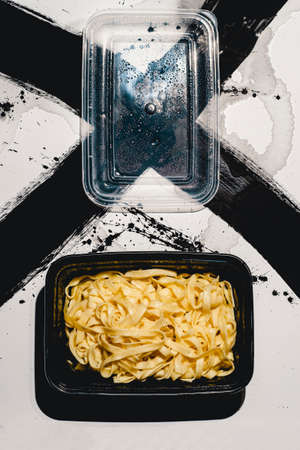 Abstract concept Italian takeout fettuccine alfredo in plastic containerの写真素材