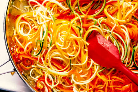 Cooking and stirring zucchini noodles in pan on stove for vegetarian pad thaiの写真素材
