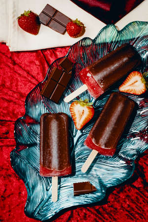 Juicy homemade strawberry icepops dipped in milk chocolateの写真素材