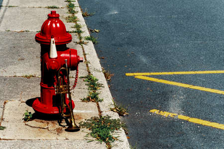 Summer jazz instrument trumpet standing alone against red fire hydrant on city street