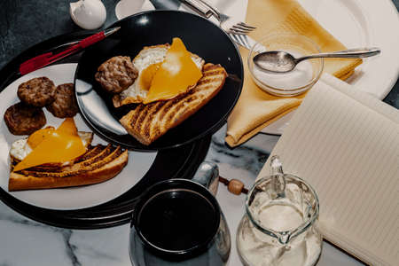 Authorâs notebook and pen at kitchen table for fancy sausage egg and cheese breakfast sandwichの写真素材