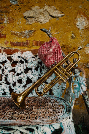 Traveling musicians trumpet and handkerchief picnic sack on a stick resting against outdoor old metal loveseatの写真素材