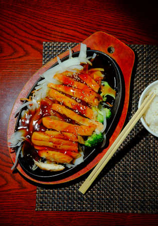 Japanese teriyaki chicken dinner served in cast iron hot plateの写真素材