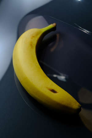 Plain ripe yellow banana on dark reflective backgroundの写真素材